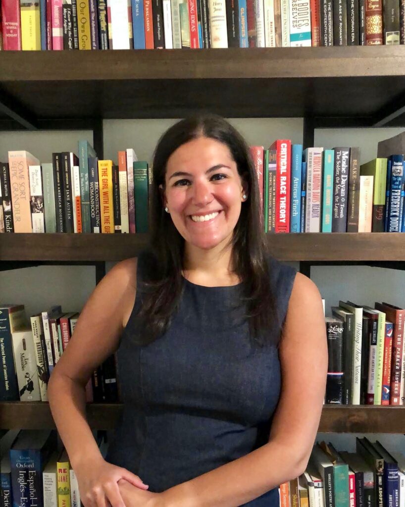 Woman posing with book shelf in background