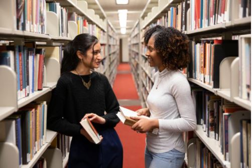 Two women talking in the book stacks