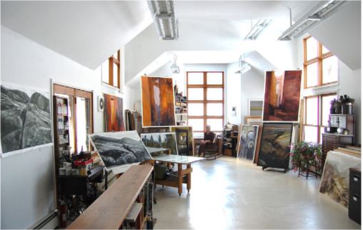 An art studio with bright light shining from above with a figure in the background