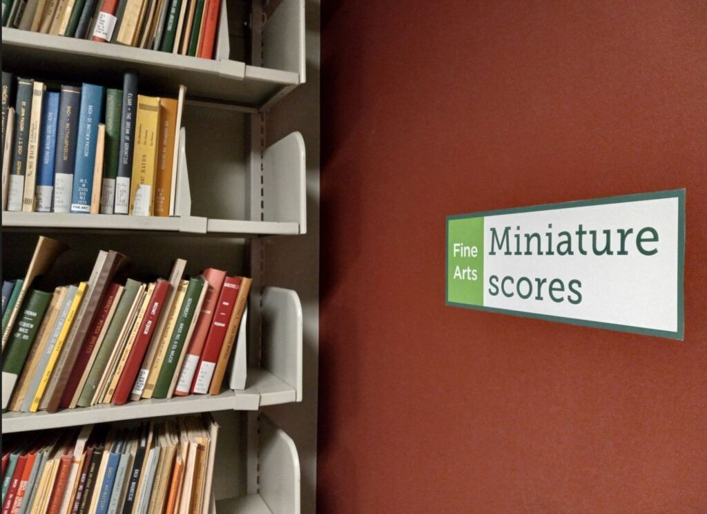 Sign that reads: miniature scores next to book shelf