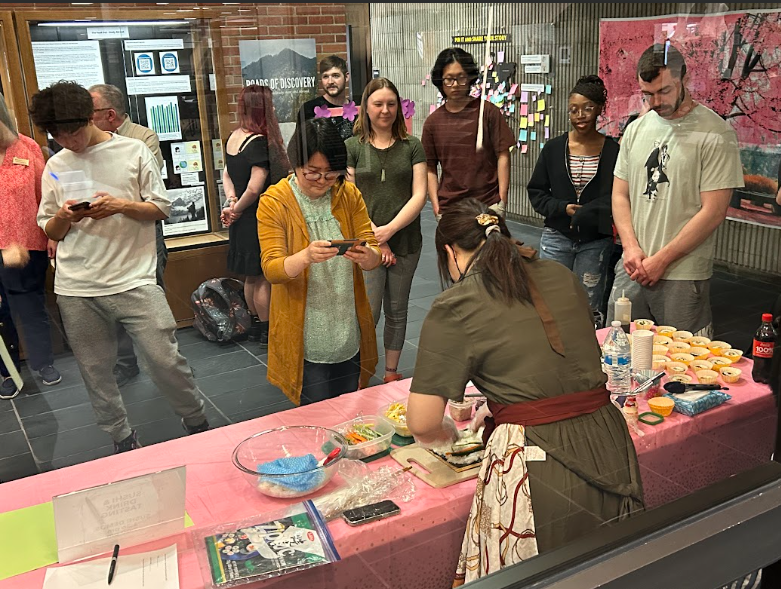 People gather and watch a demonstration of sushi being made at a Cherry Blossom Festival event held in Bartle Library.