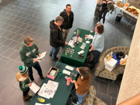 Overhead photo of alumni visiting the homecoming event "Buttons and Bagels" in the Bartle Library lobby.