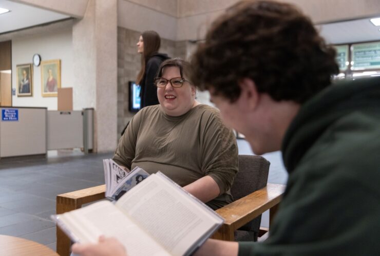 students sitting in Bartle Library lobby reading books smiling