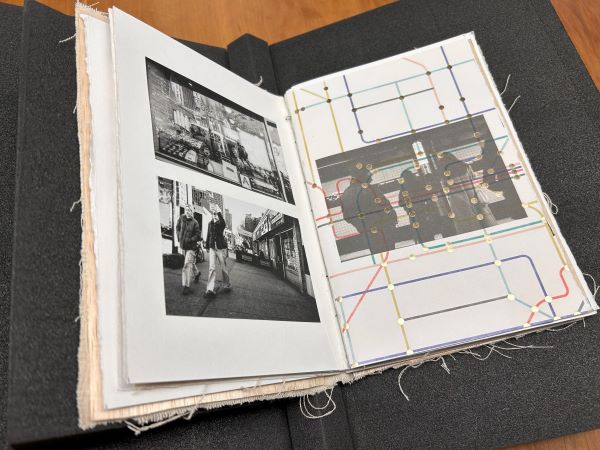 Open artists' book showing black and white photographs of New York City street scenes with a translucent page overlay of a subway map