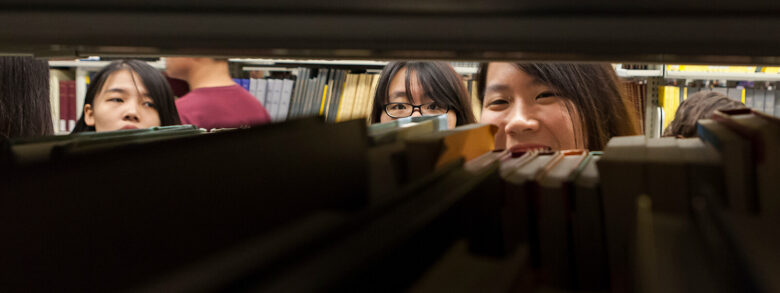 A student peeks through the shelves of the Bartle stacks