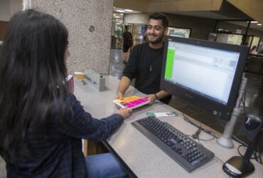 A student receives a book from the reader services desk.