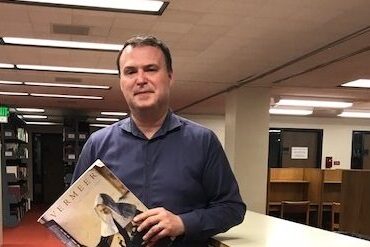 Jim Galbraith, the Libraries' Head of Collection Development, poses in the Fine Arts stacks in Bartle Library