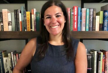 Woman posing with book shelf in background