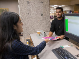 A student at the Bartle reserves desk hands a book to a student