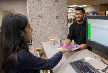 A student at the Bartle reserves desk hands a book to a student