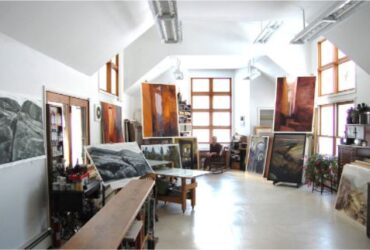 An art studio with bright light shining from above with a figure in the background