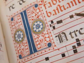 15th century blue and red hand drawn lettering on a white page with black music notes