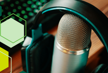 Image of a podcast recording microphone with headphones resting on top. A variety of green hexagons decorate the left side of the photo