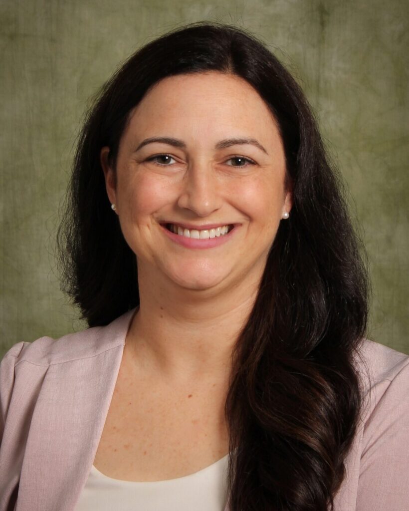 Professional portrait of Dean of Libraries Andrea Falcone in front of a green background