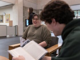 students sitting in Bartle Library lobby reading books smiling