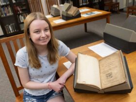 photo of first-year student Aeryn Zahn next to a rare book from the Libraries Special Collections