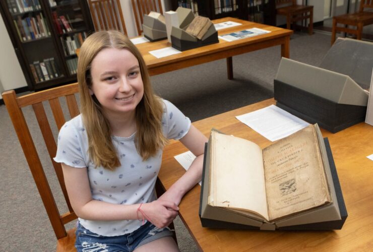photo of first-year student Aeryn Zahn next to a rare book from the Libraries Special Collections