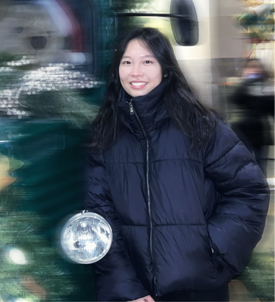 photo of Regina Lu in a coat standing next to a truck adorned with Christmas garland. 