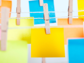 photo of various colored post-it notes hanging on a wire with clothespins.