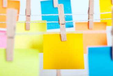 photo of various colored post-it notes hanging on a wire with clothespins.