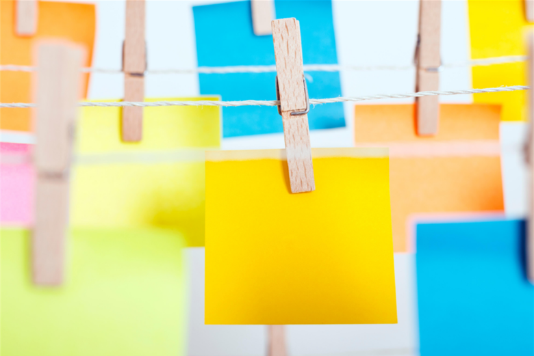 photo of various colored post-it notes hanging on a wire with clothespins.