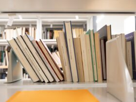 Photo of books stacked on a shelf leaning against each other.