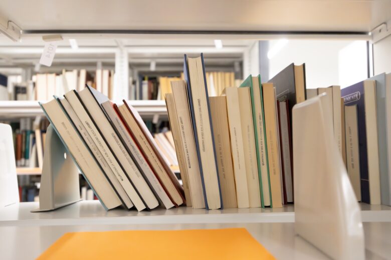 Photo of books stacked on a shelf leaning against each other.