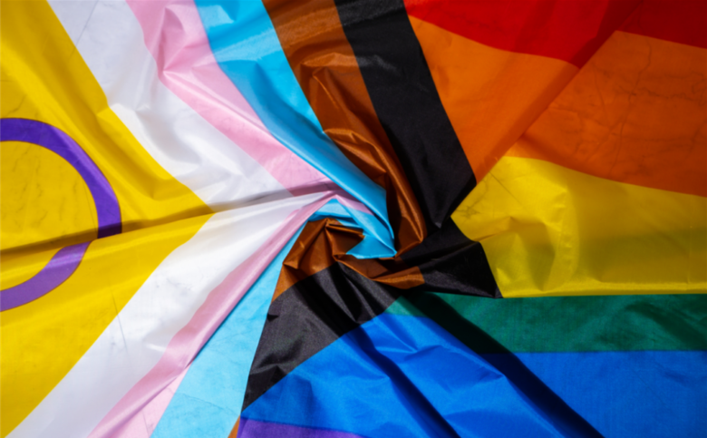 Photo of an intersex-inclusive progress pride flag swirled as it lays on a flat surface.