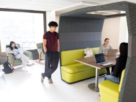 students gathered on the third floor of Bartle Library using some of the brightly colored furniture including a booth-style table and rocking chair.