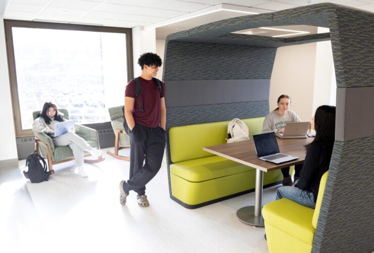 students gathered on the third floor of Bartle Library using some of the brightly colored furniture including a booth-style table and rocking chair.