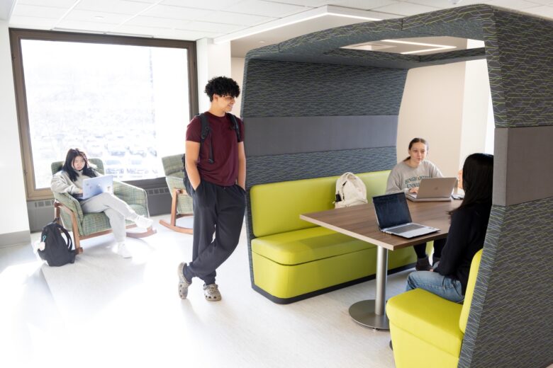 students gathered on the third floor of Bartle Library using some of the brightly colored furniture including a booth-style table and rocking chair.