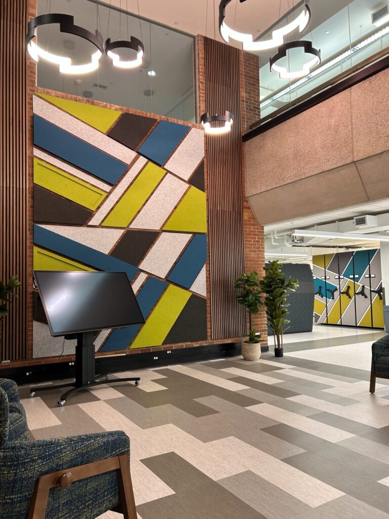 Photo of the Research showcase on the third floor of Bartle Library. Features include modern hanging lighting, a mosaic wall and a digital display.