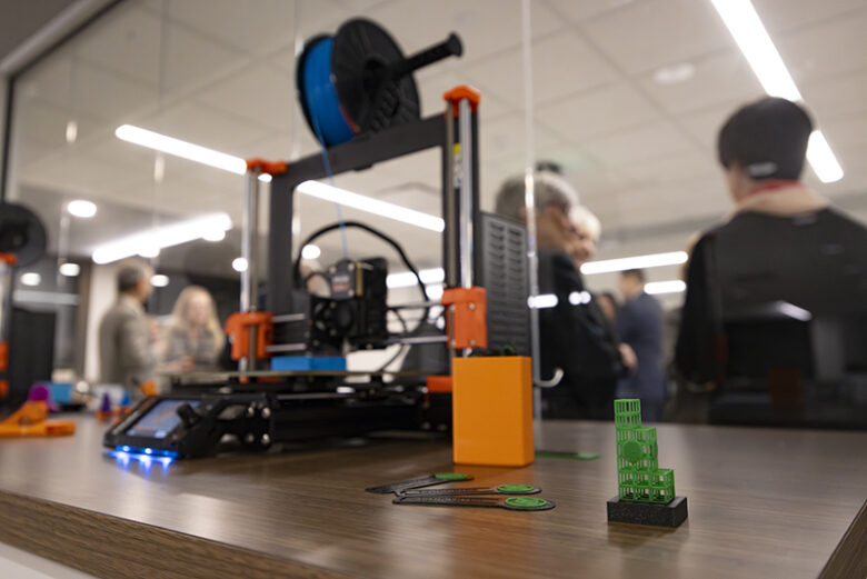 3D printer on display alongside featured items printed out of moldable plastic.