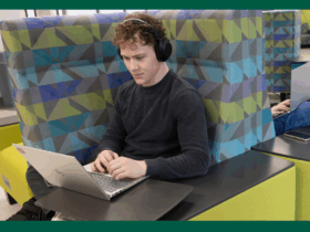 student sitting and working on a laptop with headphones on.