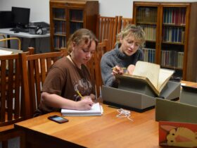 Two students seated at a table looking at a book in Special Collections.