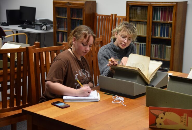 Two students seated at a table looking at a book in Special Collections.