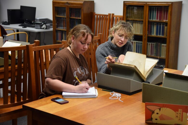 Two students seated at a table looking at a book in Special Collections.