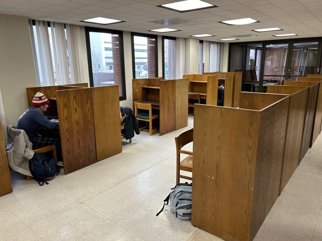 Photo of a few rows of individual study carrels next to windows looking outside.