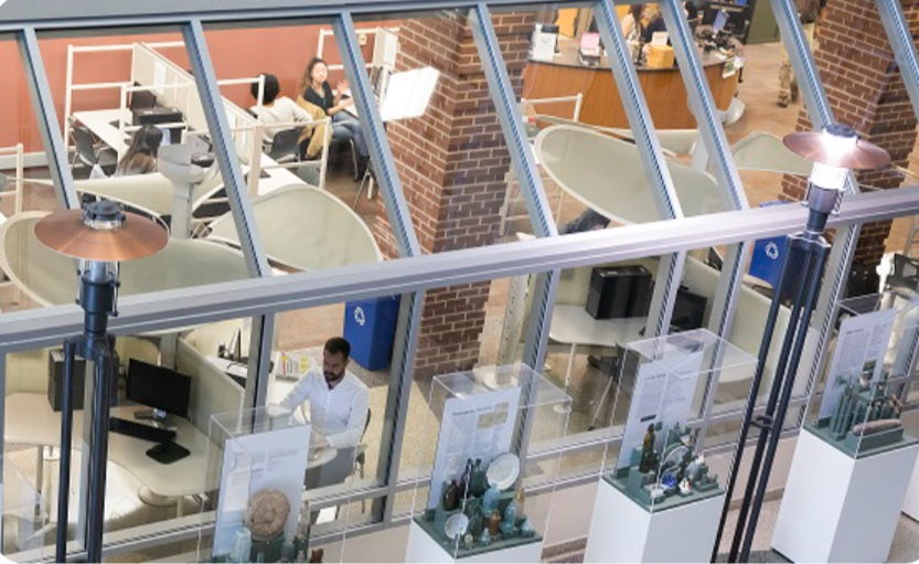 a photo looking into the UDC Library from the UDC Atrium showcasing various cubicles and study spots.