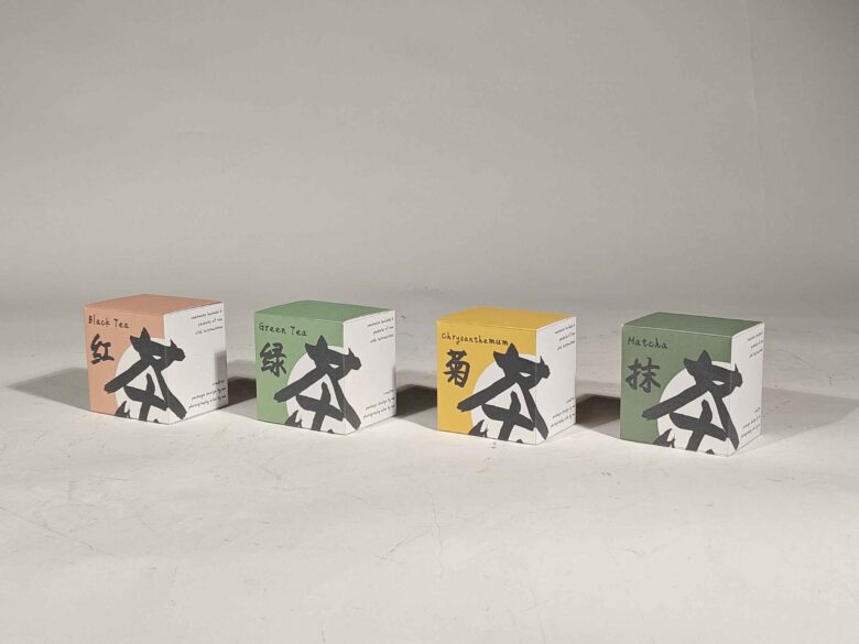 Four tea boxes displayed in a white setting. "Cha" by Sammy Feng was selected as the 2025 Purchase Prize winner.