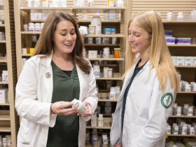 Two women from SOPPS look at a prescription bottle at Pharmacy Practice at Wegmans.