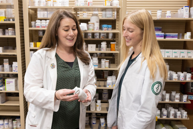 Two women from SOPPS look at a prescription bottle at Pharmacy Practice at Wegmans.