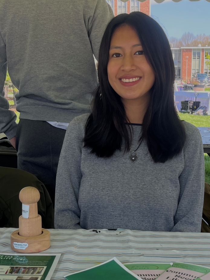 Ashley Maurad sits at a table with various items from the Sustainability Hub on display.