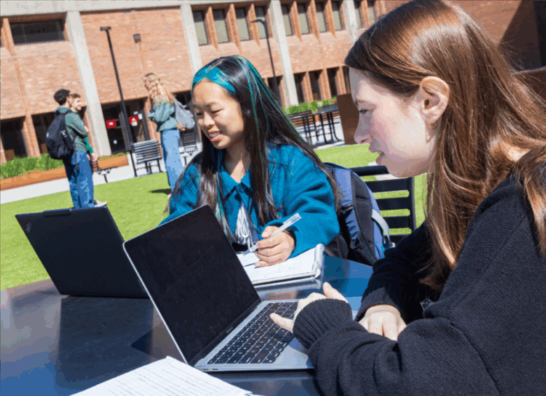 Students sitting outside Bartle Library studying on laptops.
